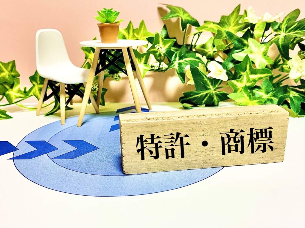 商標登録や特許取得の重要性をイメージした、木製プレートと観葉植物の構成写真